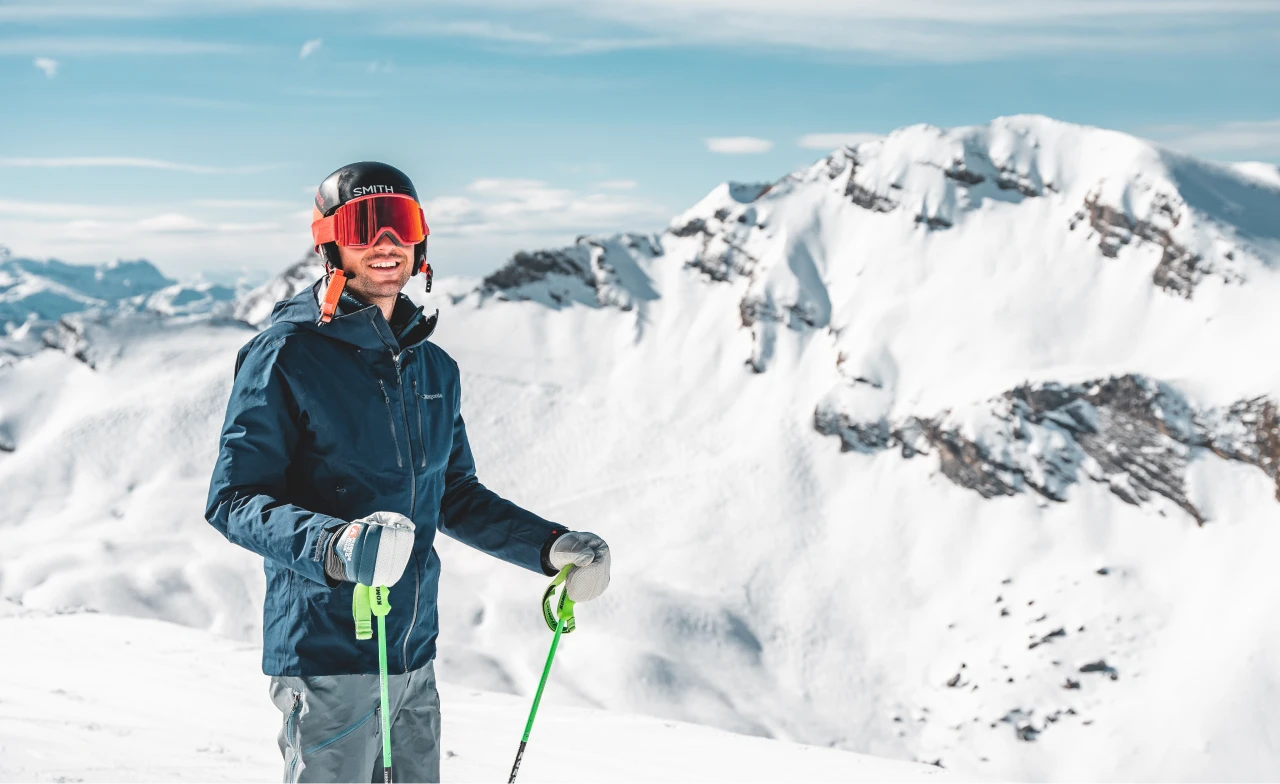 Un moniteur de ski debout et souriant avec une montagne enneigée derrière eux